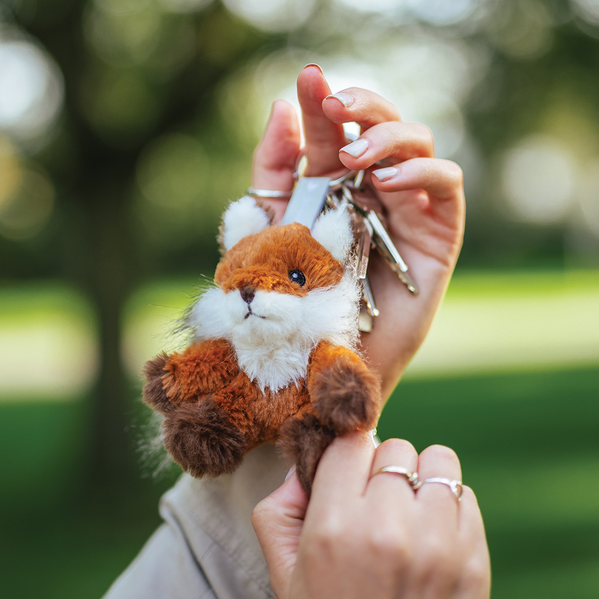 flauschiger Fuchs Schlüsselanhänger, haltend mit grünem Hintergrund