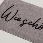 graue Fußmatte mit einem schwarzer Schrift "Wie schön dich zu sehen"