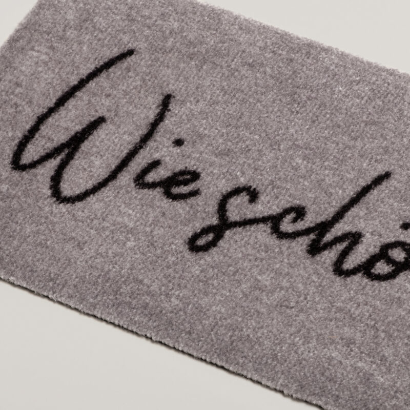 graue Fußmatte mit einem schwarzer Schrift "Wie schön dich zu sehen"