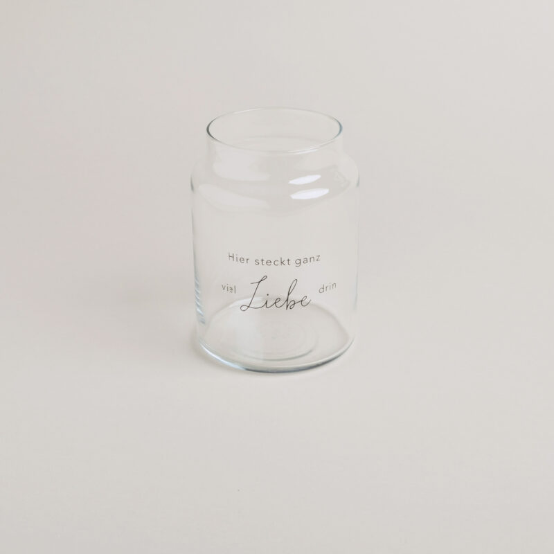 Glasvase mit der schwarzen Aufschrift "Hier steckt ganz viel Liebe drin"