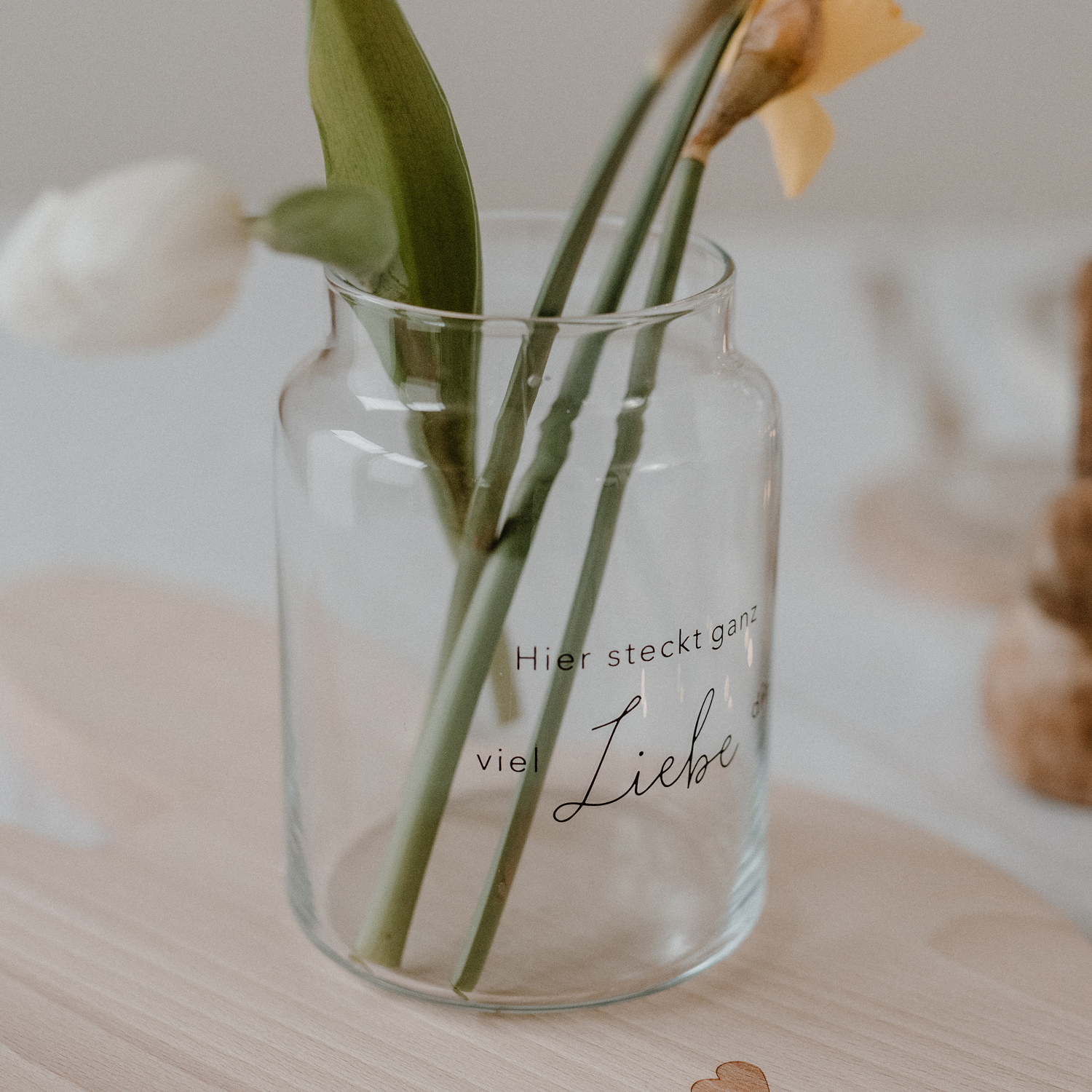 Glasvase mit der schwarzen Aufschrift "Hier steckt ganz viel Liebe drin"